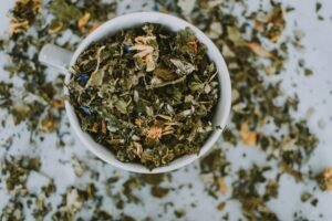 Overhead shot of a cup with a blend of dried herbal tea leaves and flowers.