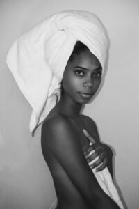 Artistic black and white portrait of a woman with a towel turban, exuding elegance and confidence.